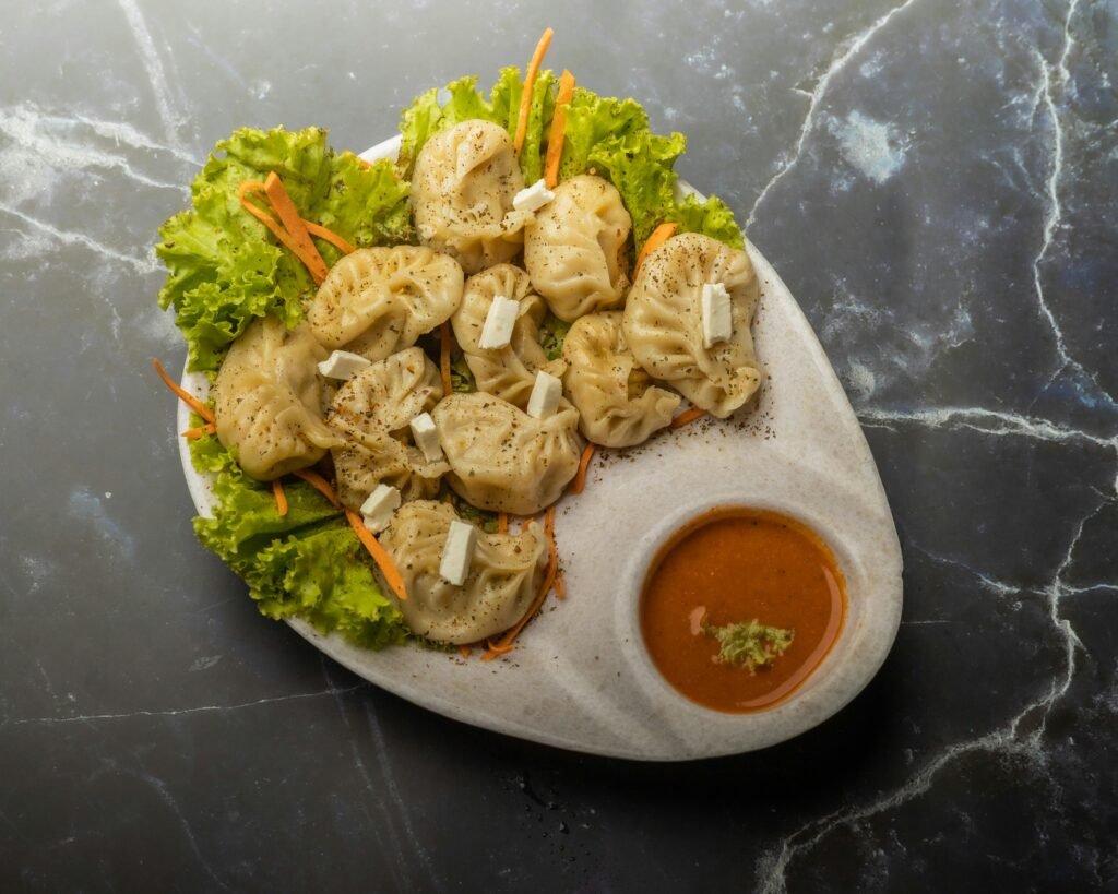 Tasty homemade paneer momos served with spicy chutney on a marble background.